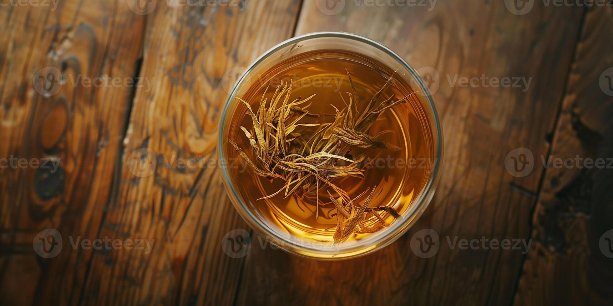 Black tea leaves floating in clear hot water in a glass cup on a wooden table, culinary photography photo