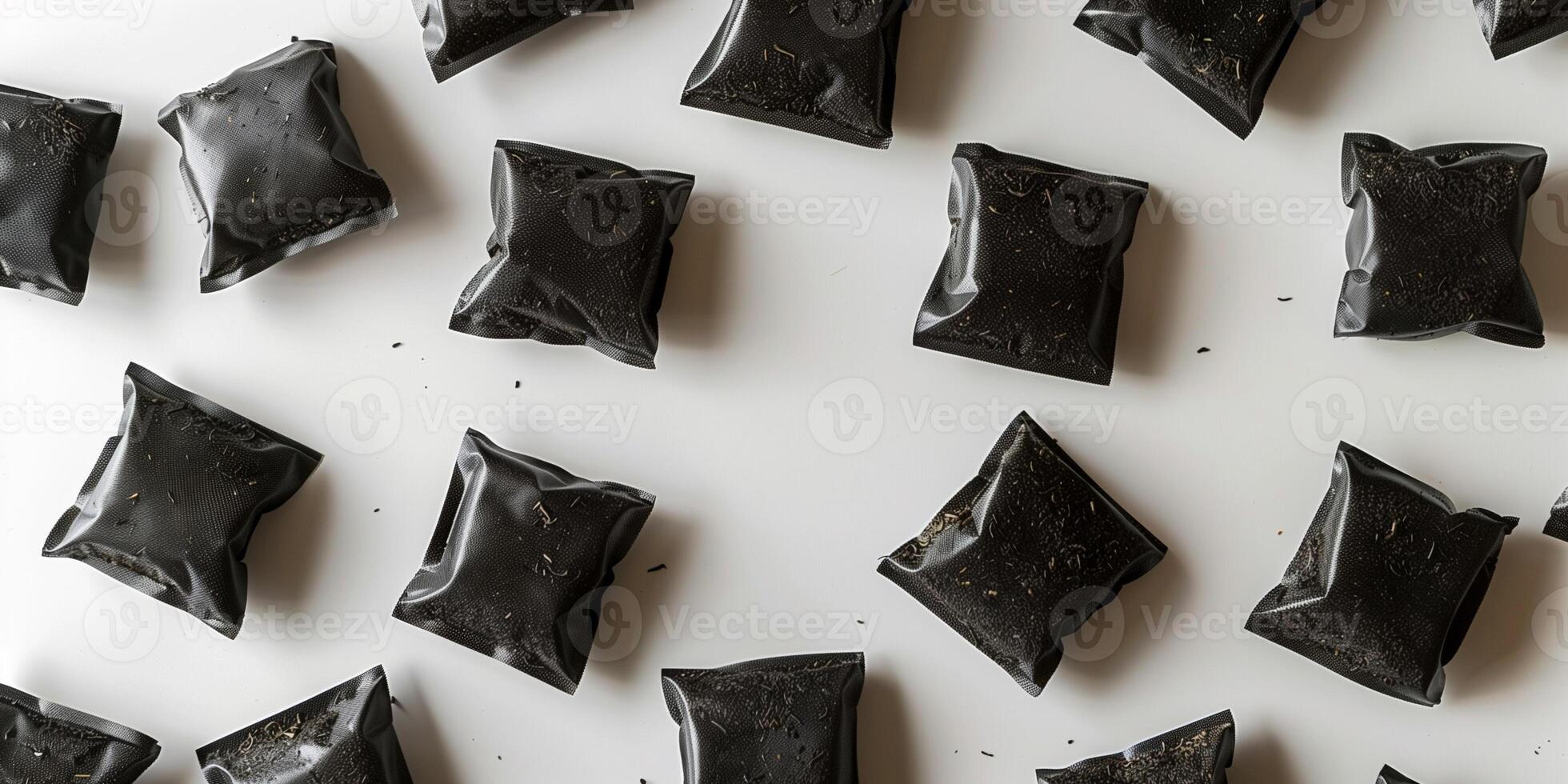 Black tea bags arranged in a circular pattern on a white surface, photorealistic food photo