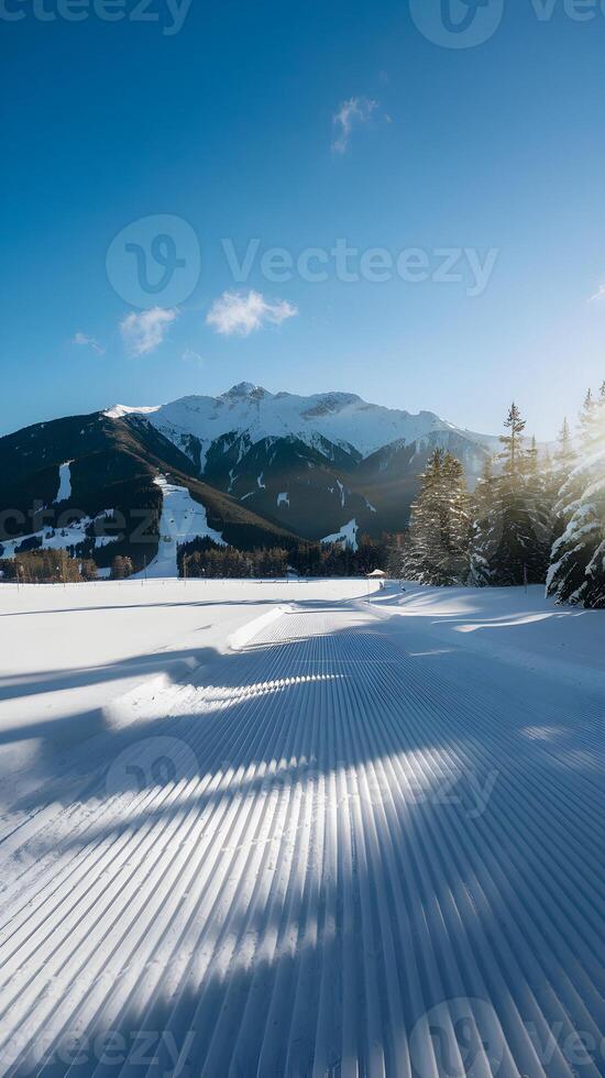 Pristine snowy landscape with groomed snow patterns leading to distant snowy mountains Vertical Mobile Wallpaper photo