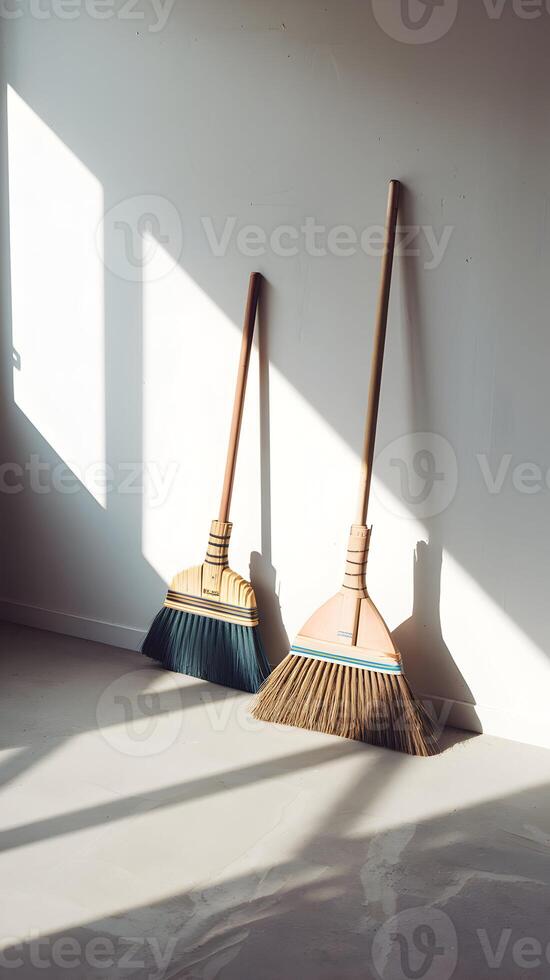 Empty room with sunlight casting shadows, brooms leaning in serene simplicity Vertical Mobile Wallpaper photo