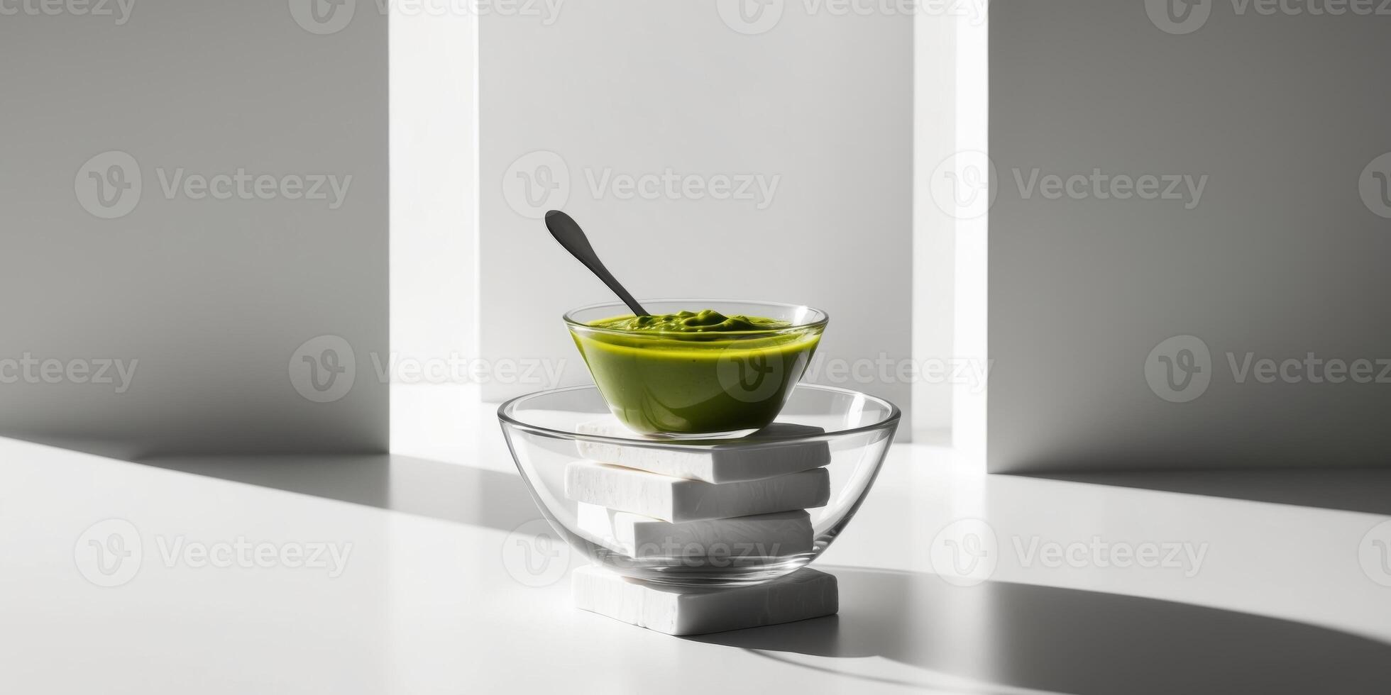 Green sauce in glass bowl atop stack of square blocks of cheese black background vertical format. photo