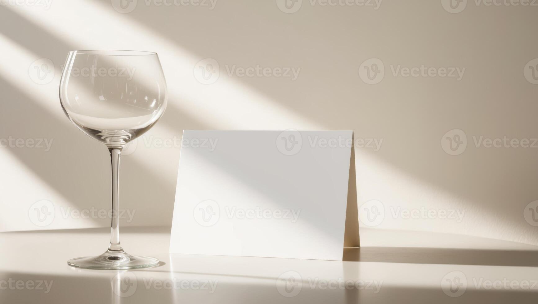 A white card with a blank space sits on a table next to a wine glass. photo
