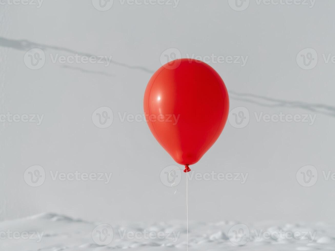 a bright red balloon with a string on a white backdrop. photo