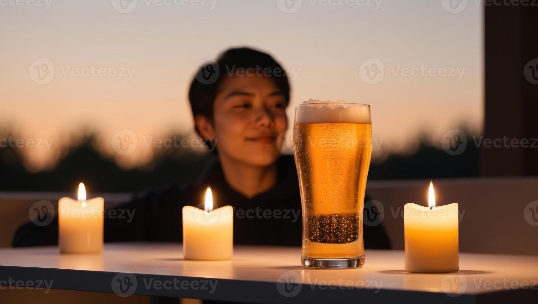 Enjoying a chilled glass of beer beside glowing candles at dusk. photo