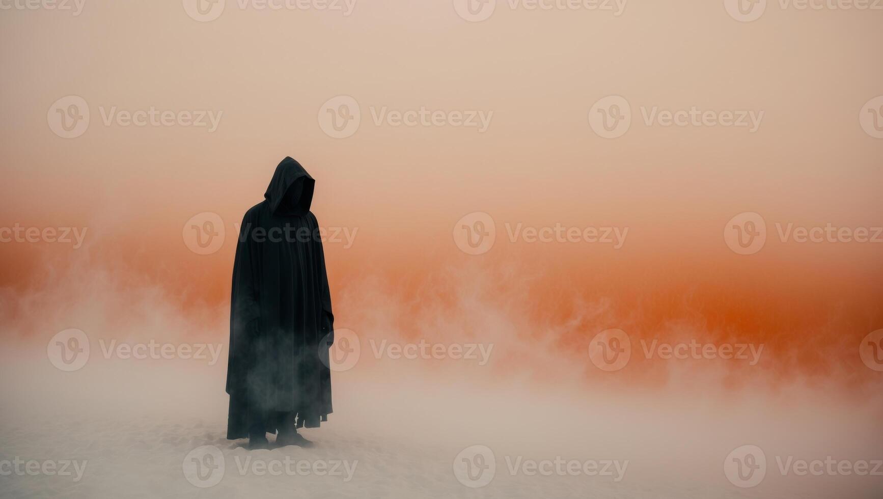 Mysterious hooded figure in an orange misty landscape. photo