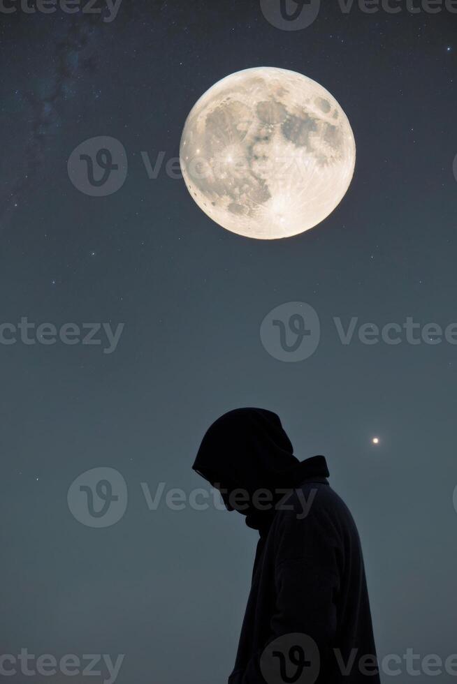 A figure contemplates under a glowing moon. photo