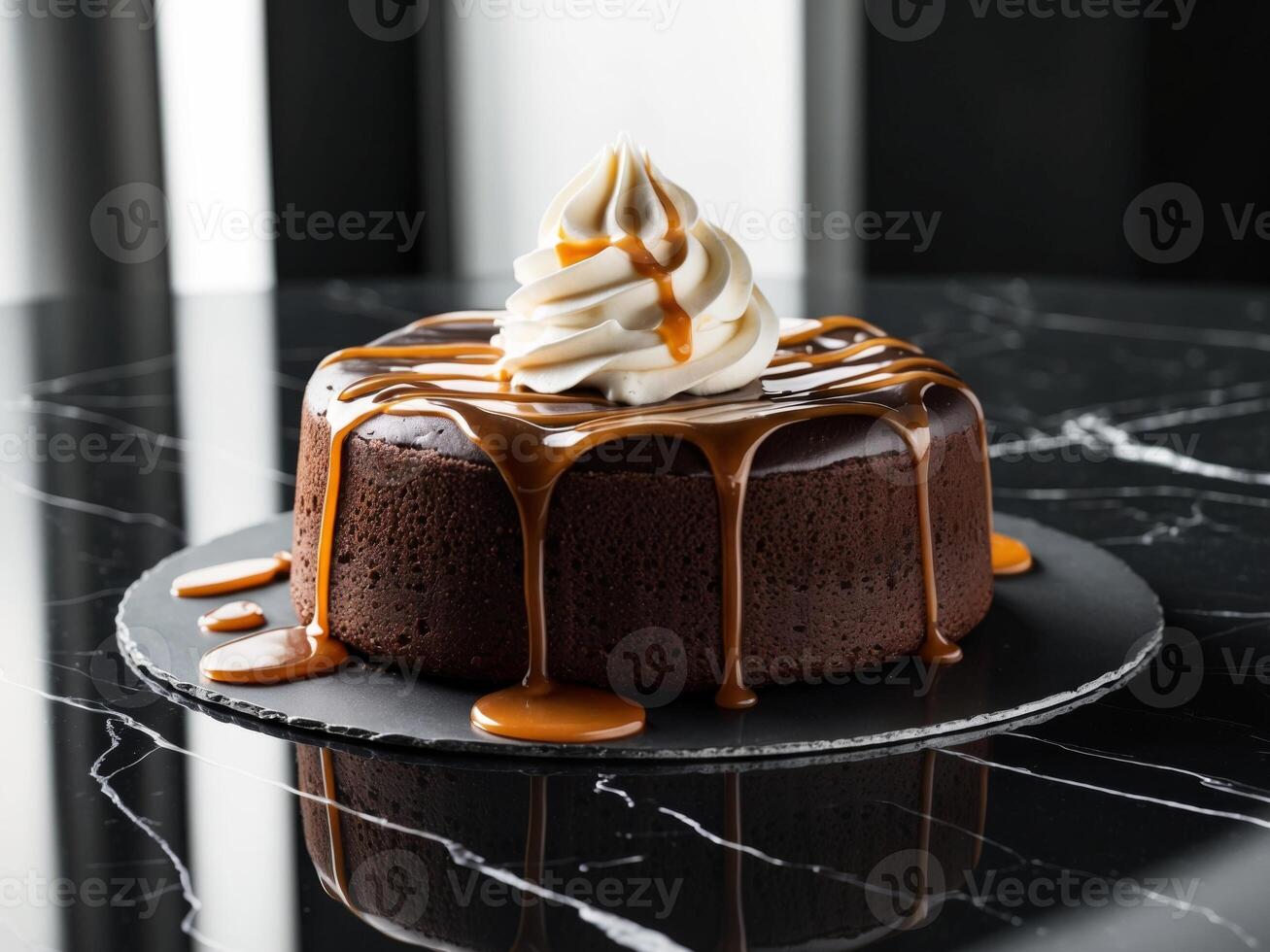 A chocolate cake with whipped cream and caramel drizzle sits on a black marble surface. photo