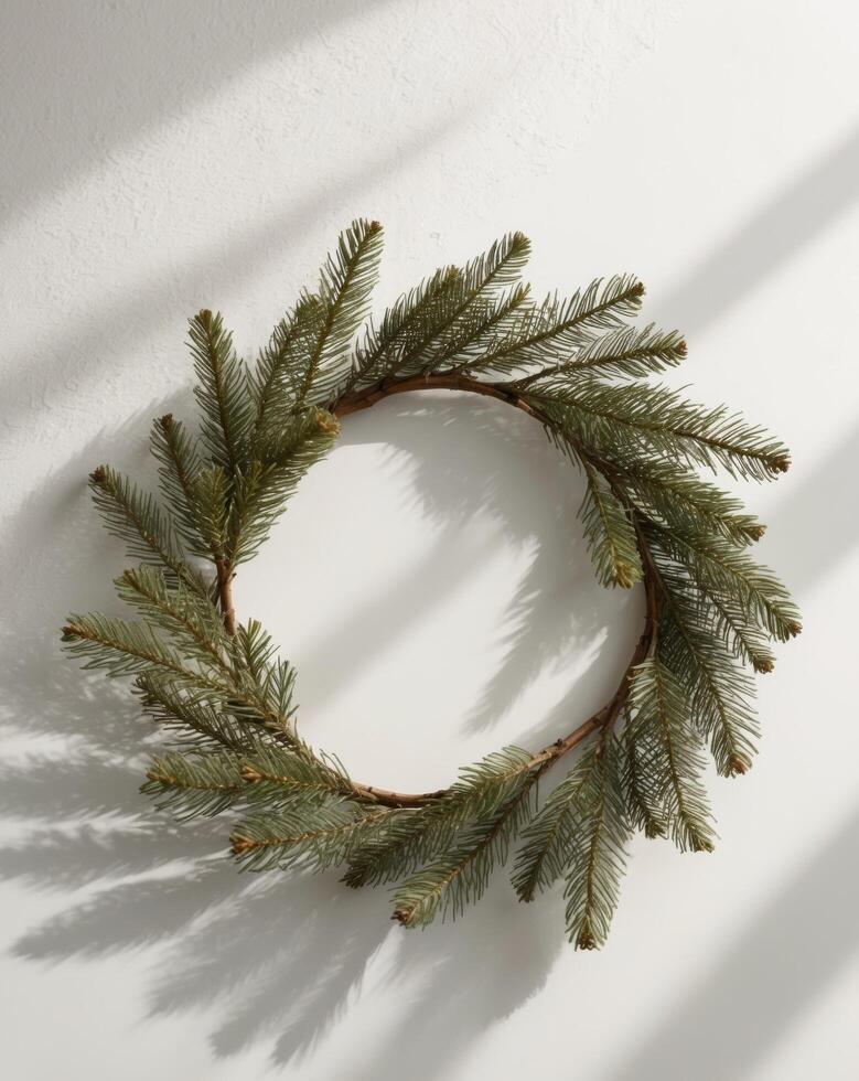 A simple wreath made from pine branches placed on a clean white surface. photo