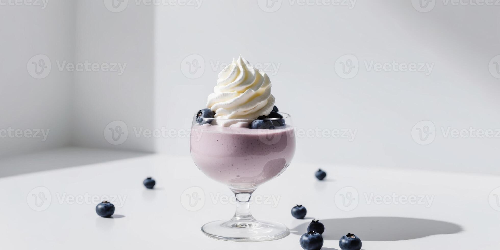 A glass of smoothie with whipped cream and blueberries on top. photo