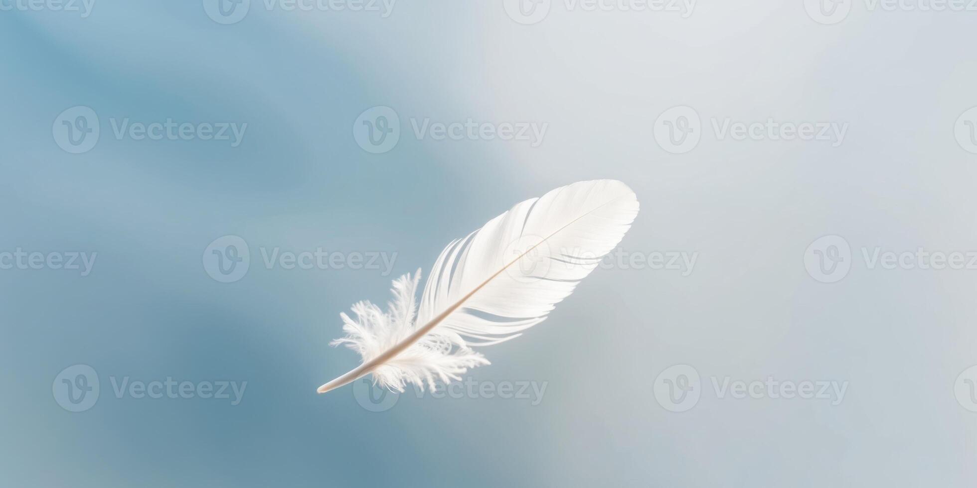 Nature showcases serenity with a delicate white feather gliding on a soft blue background. photo