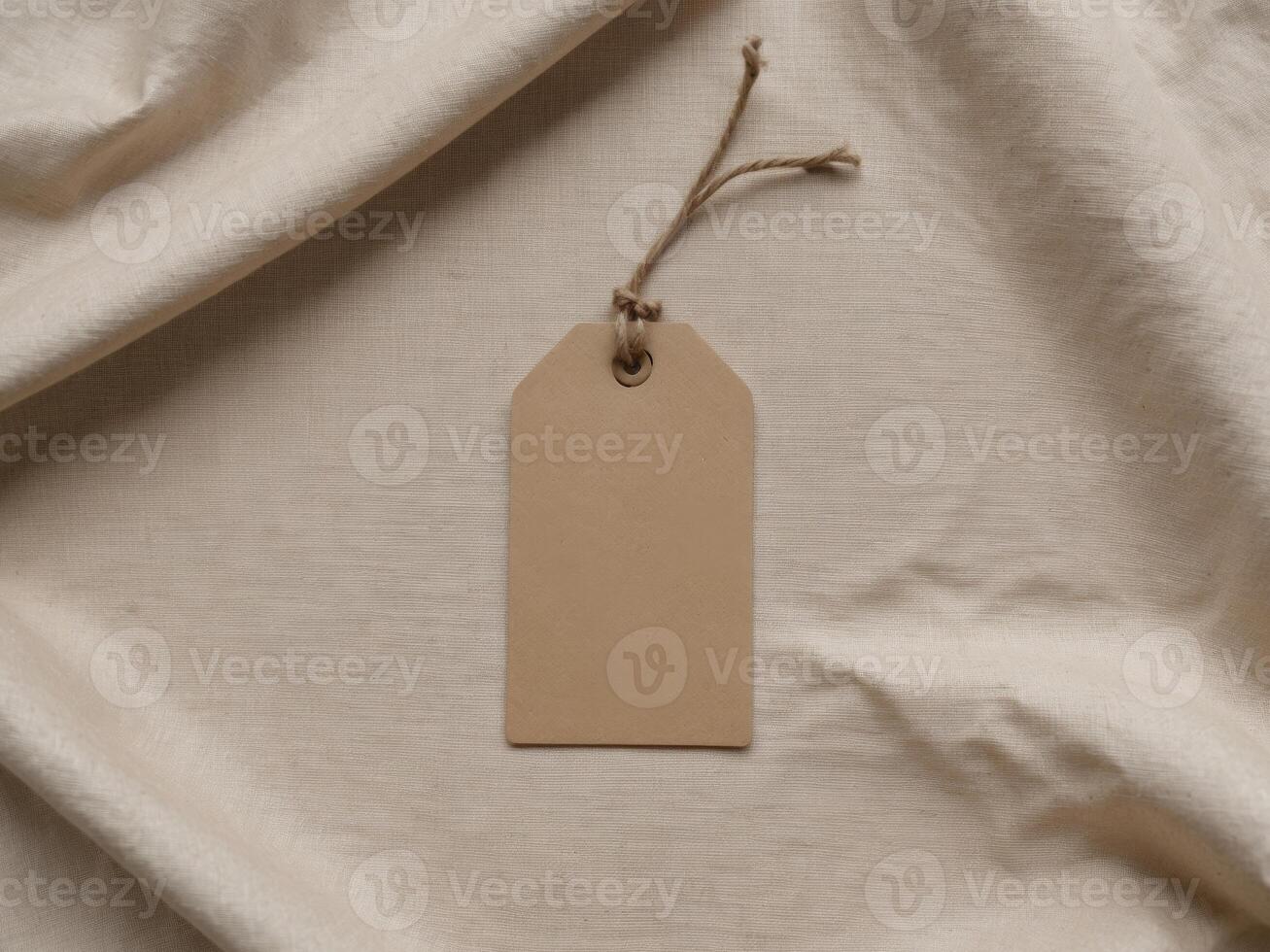 Blank Kraft Paper Tag With Rustic String Loop on Textured Fabric Background. photo