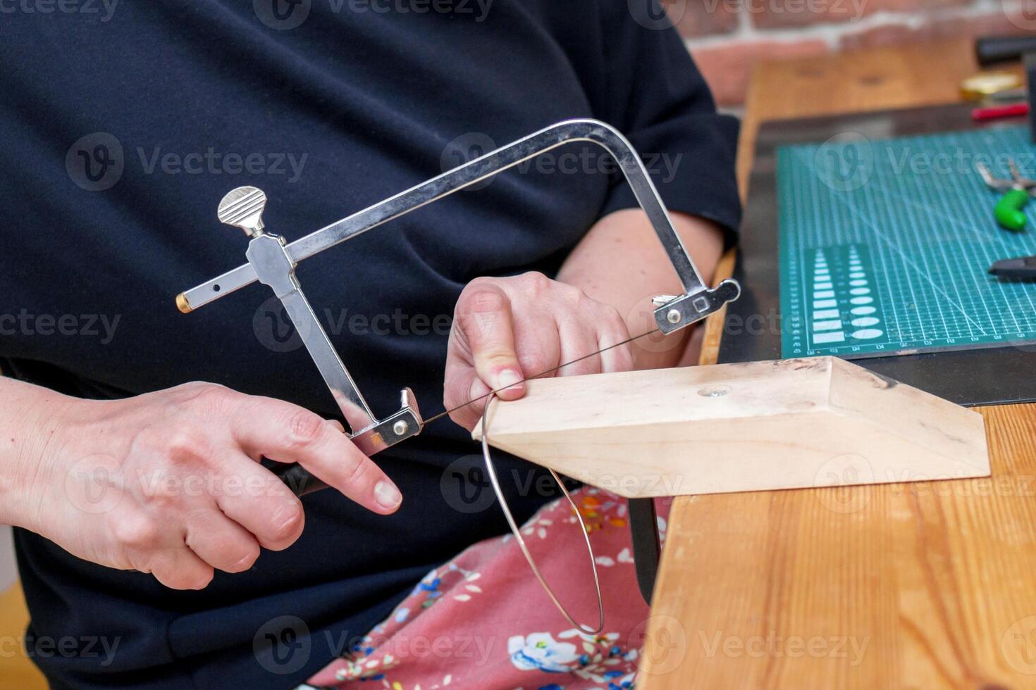 Skilled craftsperson expertly sawing through metal using a precision jewelers saw tool in workshop. photo