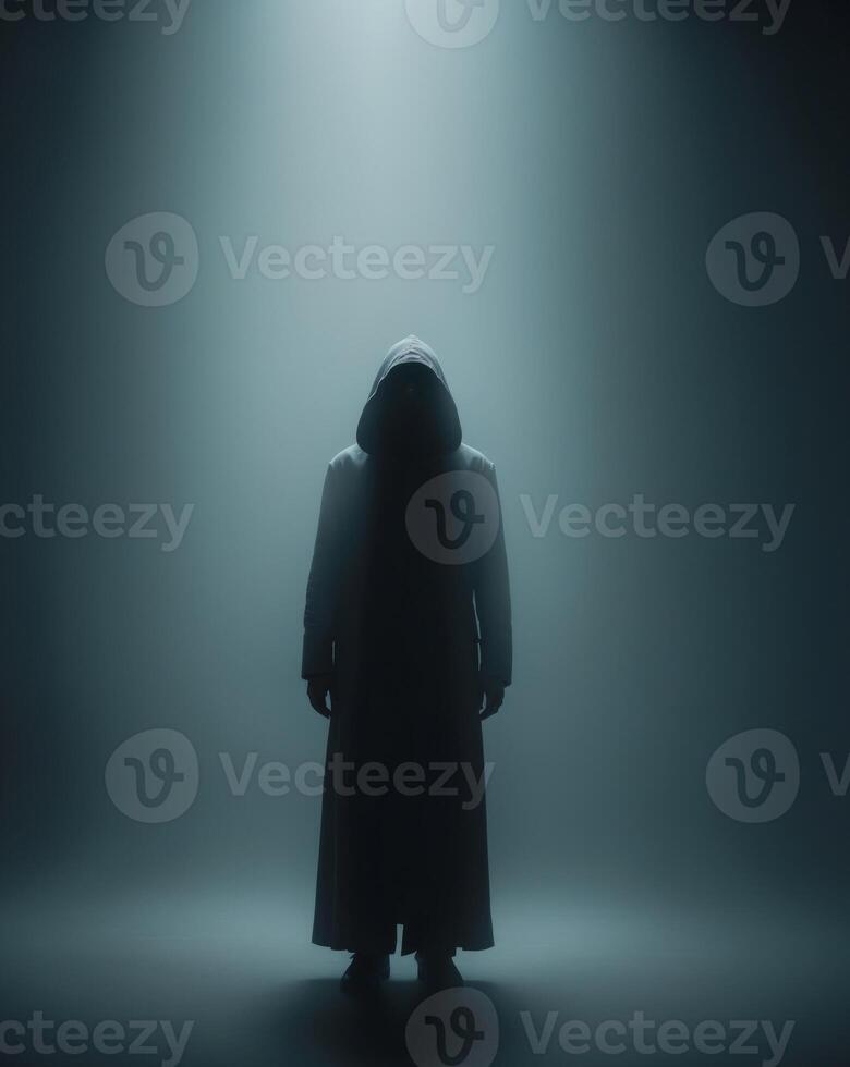 A man in a hooded robe standing in the dark photo