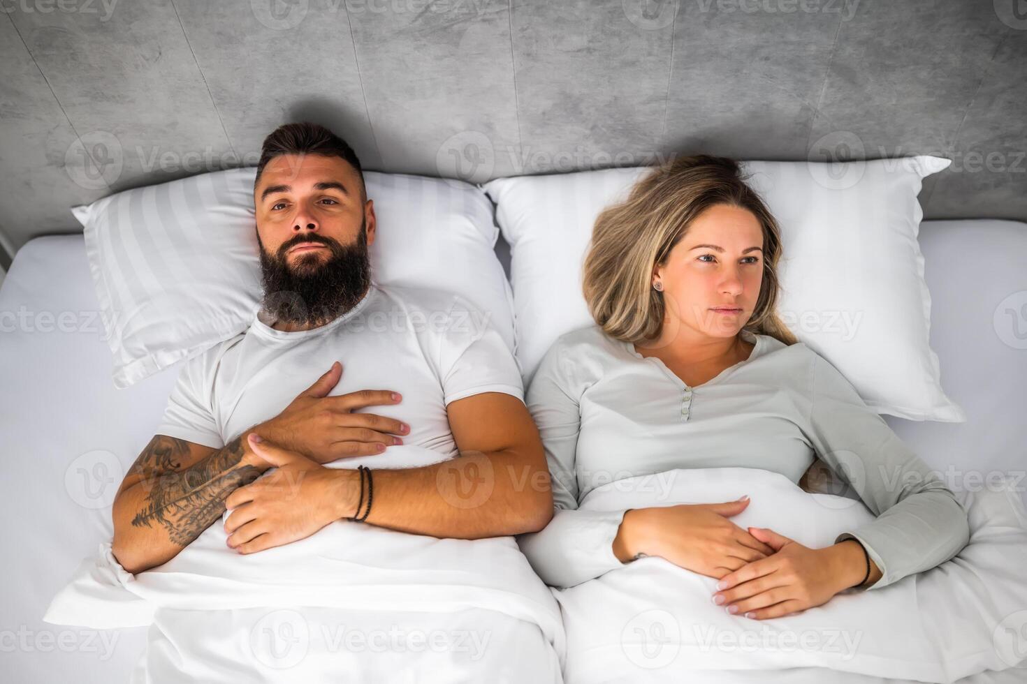 Couple is lying in bed. They are angry and not talking to each other. photo
