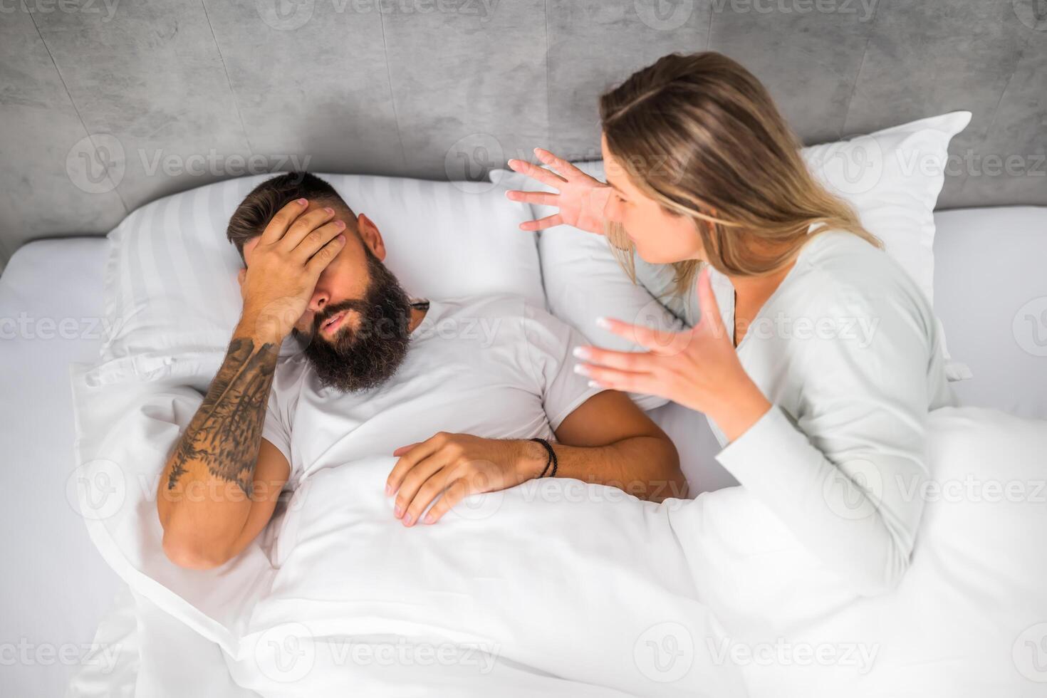 Couple is lying in bed and arguing. The woman is angry with the man. photo