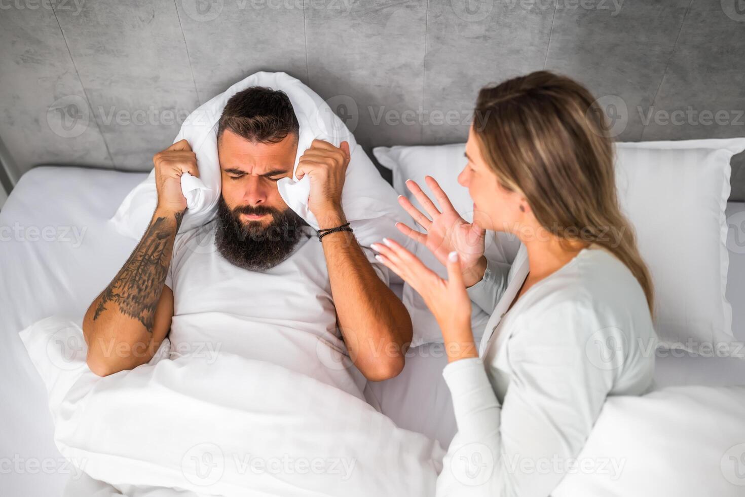 Couple is lying in bed and arguing. The woman is angry with the man. photo