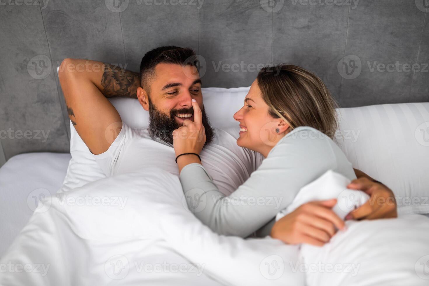 Young happy loving couple is lying in bed in the morning. They are having fun and smiling. photo