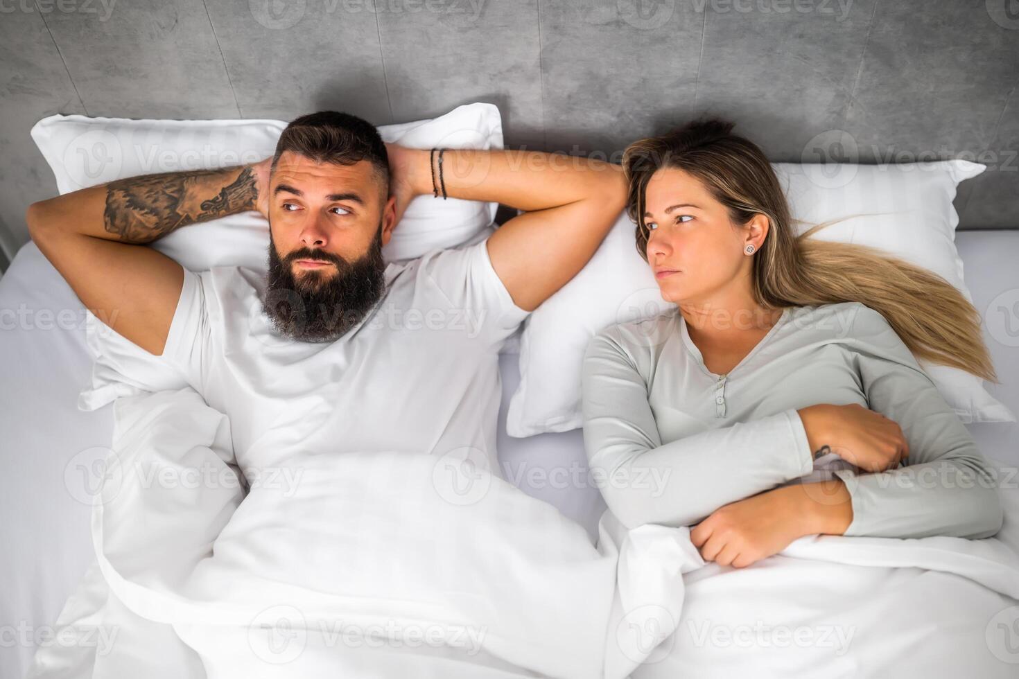 Couple is lying in bed. They are angry and not talking to each other. photo