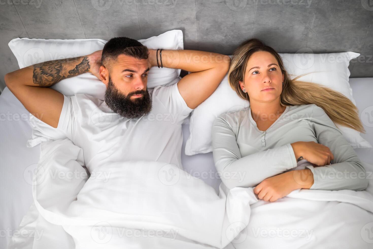 Couple is lying in bed. They are angry and not talking to each other. photo