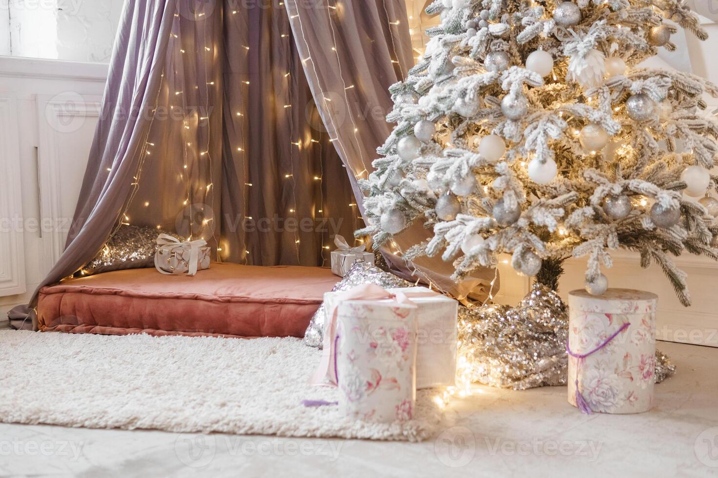 A Christmas tree sprinkled with artificial snow and a tent decorated with a luminous garland in the New Year's interior. Background for New Year wallpapers and postcards. photo