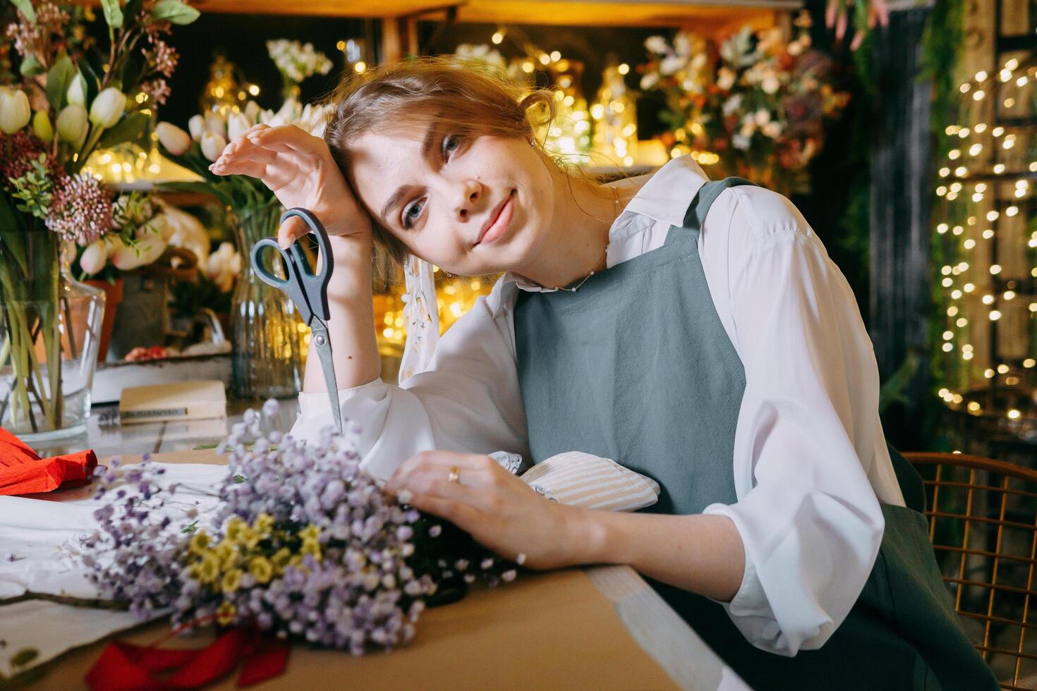 A woman in her florist shop collects bouquets of flowers. The concept of a small business. Bouquets of tulips for the holiday on March 8. photo