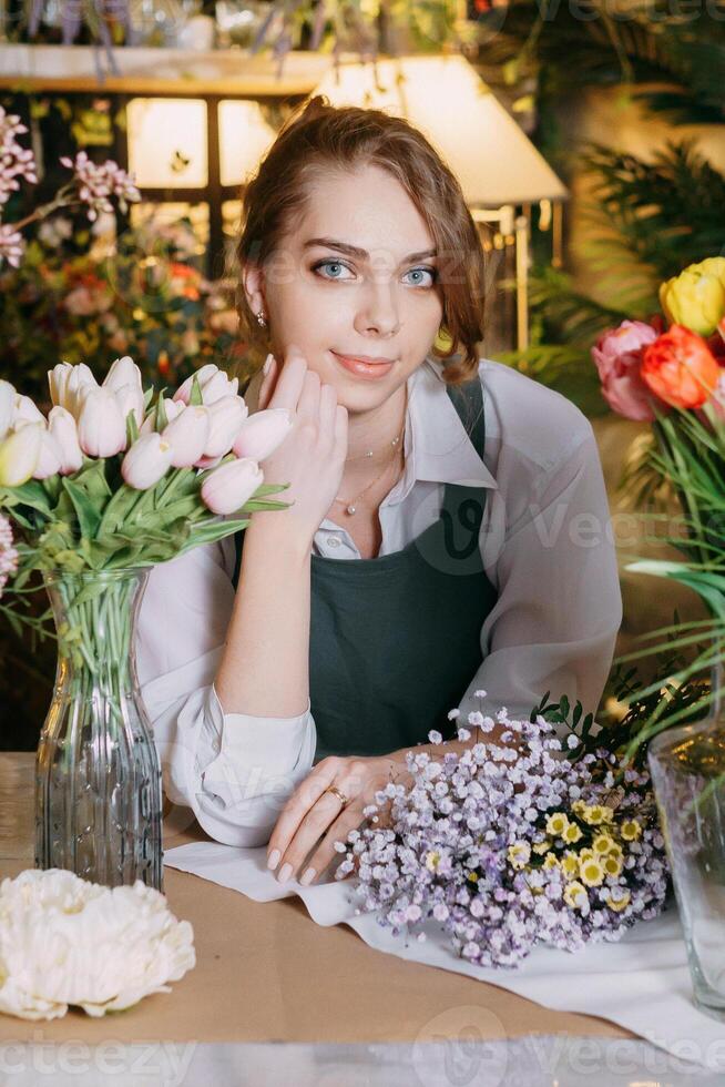A woman in her florist shop collects bouquets of flowers. The concept of a small business. Bouquets of tulips for the holiday on March 8. photo