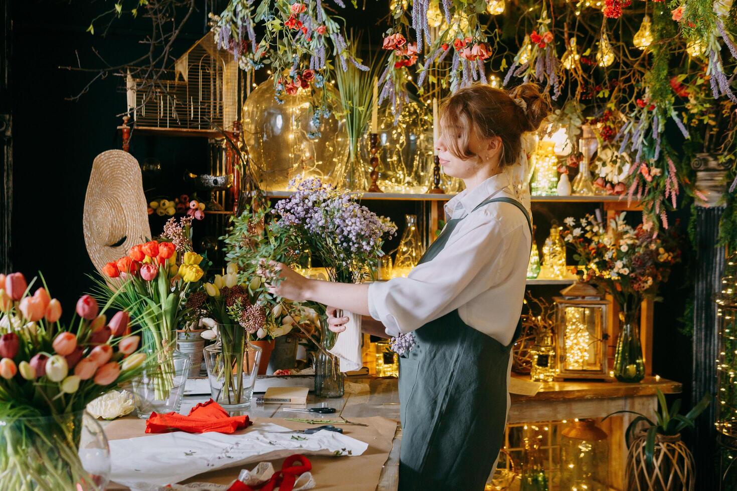 A woman in her florist shop collects bouquets of flowers. The concept of a small business. Bouquets of tulips for the holiday on March 8. photo