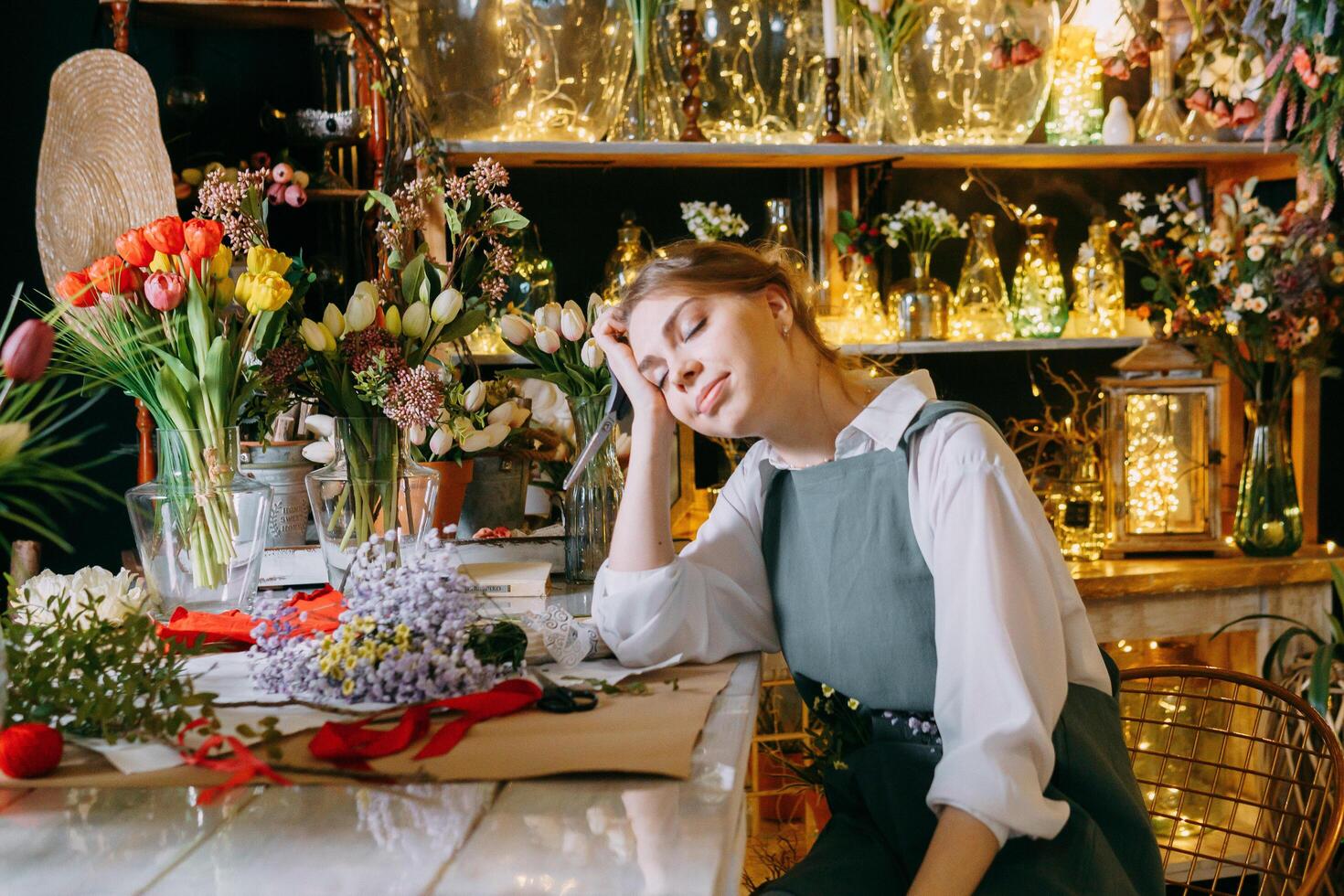 A woman in her florist shop collects bouquets of flowers. The concept of a small business. Bouquets of tulips for the holiday on March 8. photo