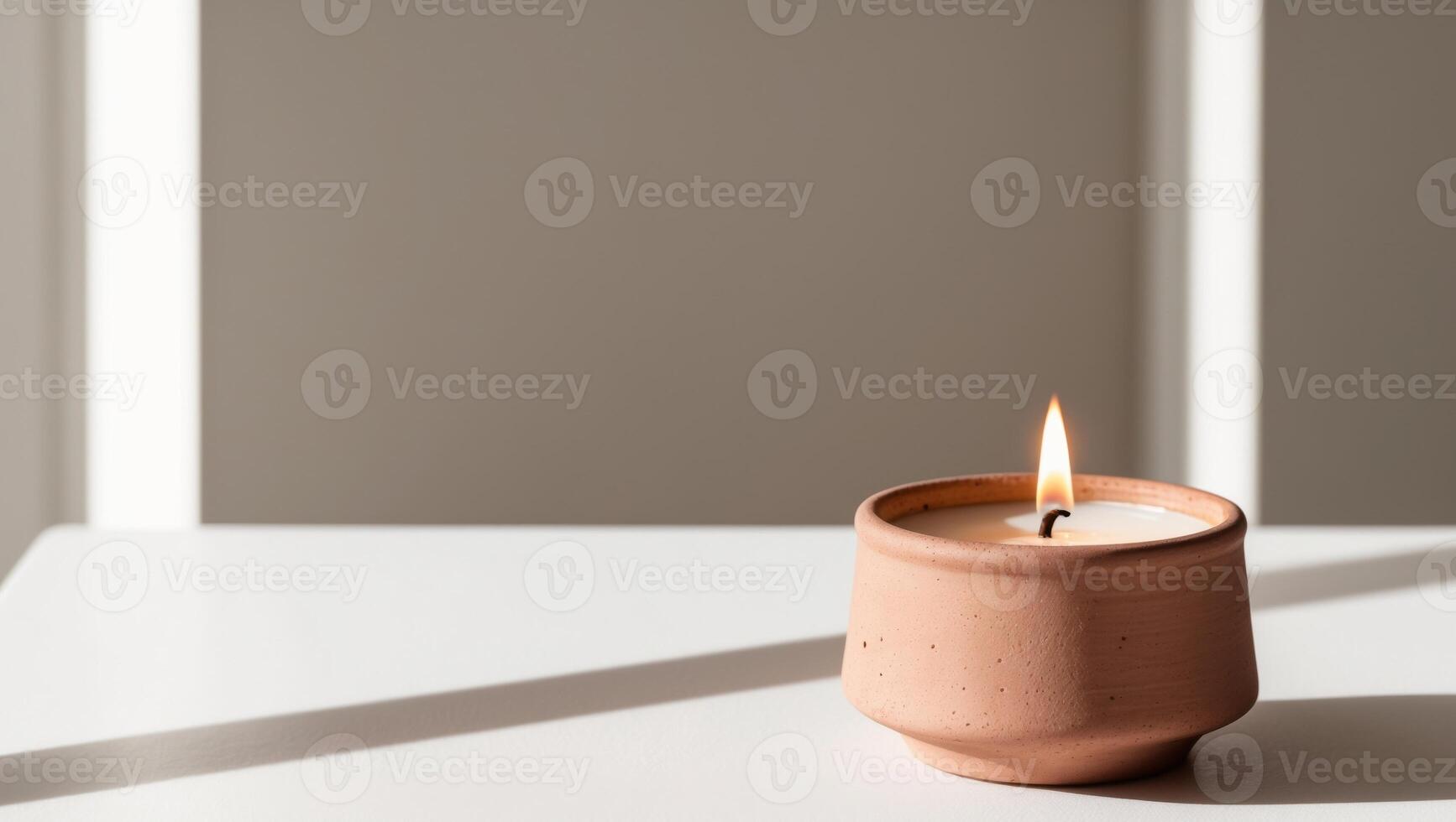 A candle is sitting on a table in front of a window photo