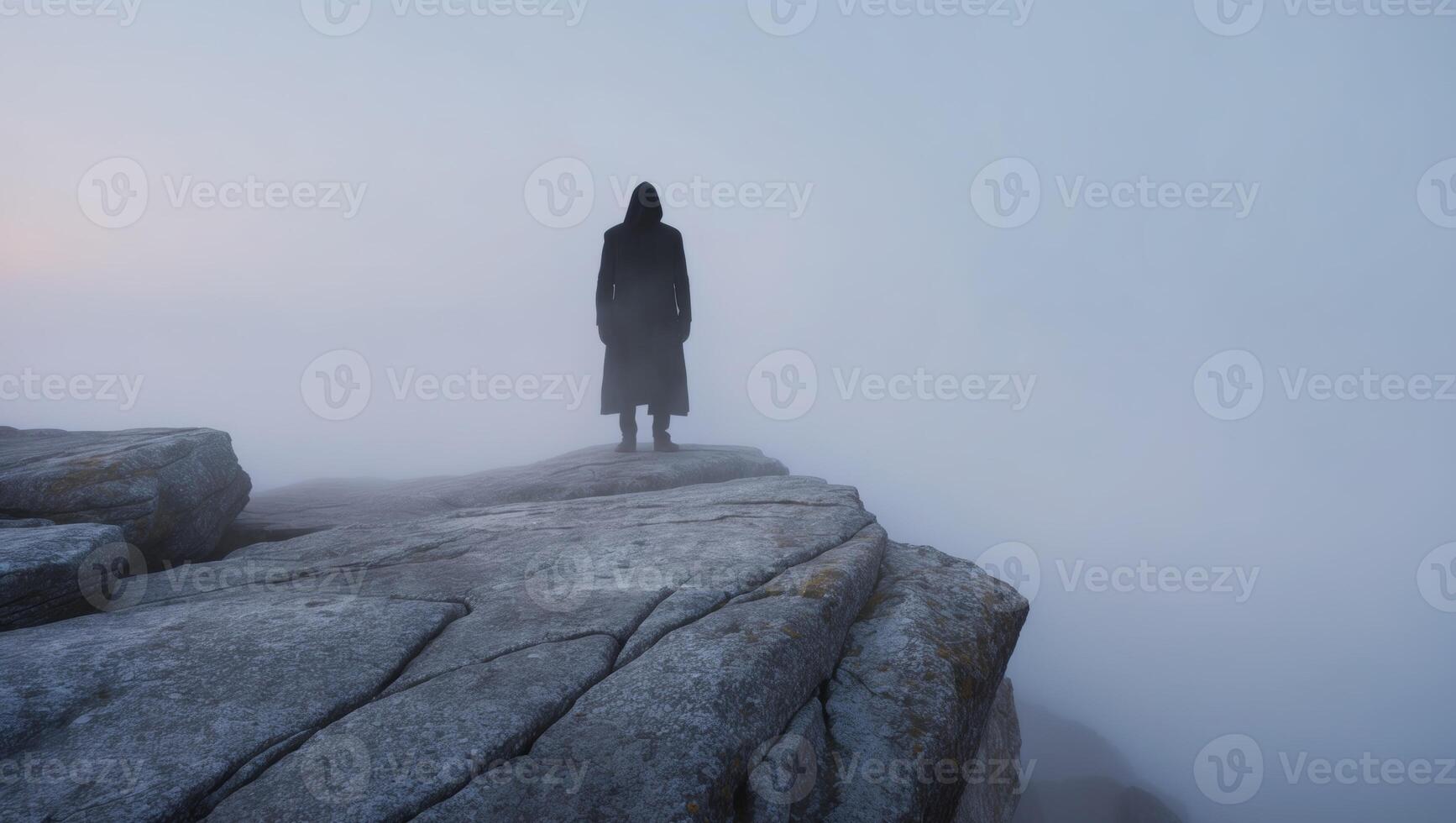 A person standing on top of a rock in the fog photo