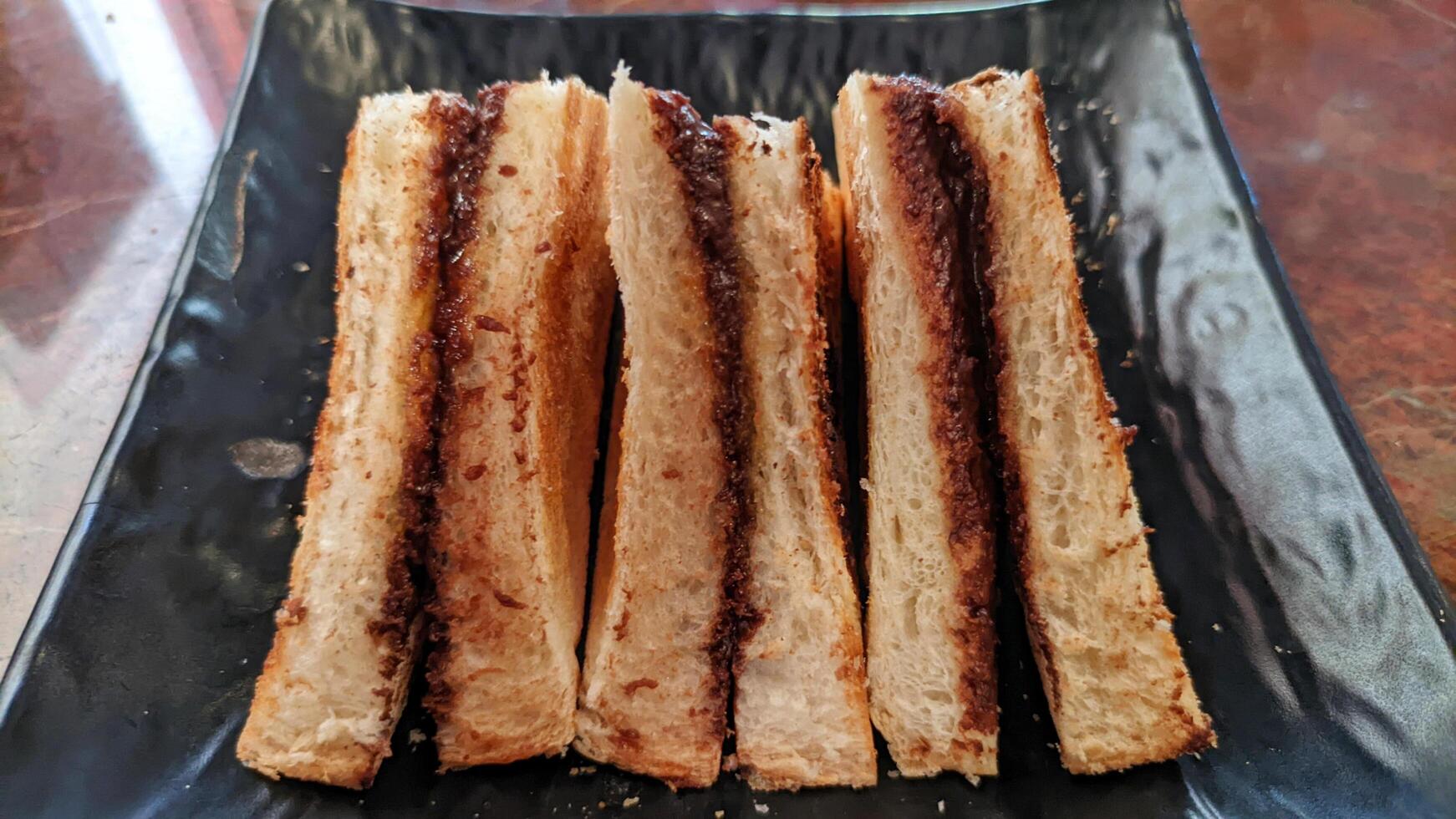 Close up of toast with homemade chocolate spread served on a black plate. photo