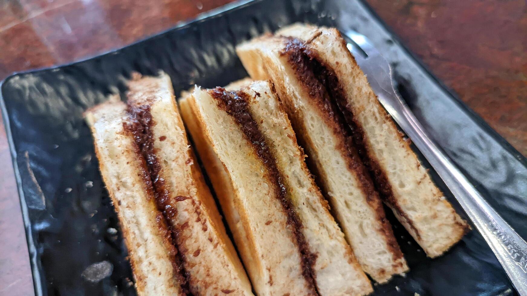 Close up of toast with homemade chocolate spread served on a black plate. photo