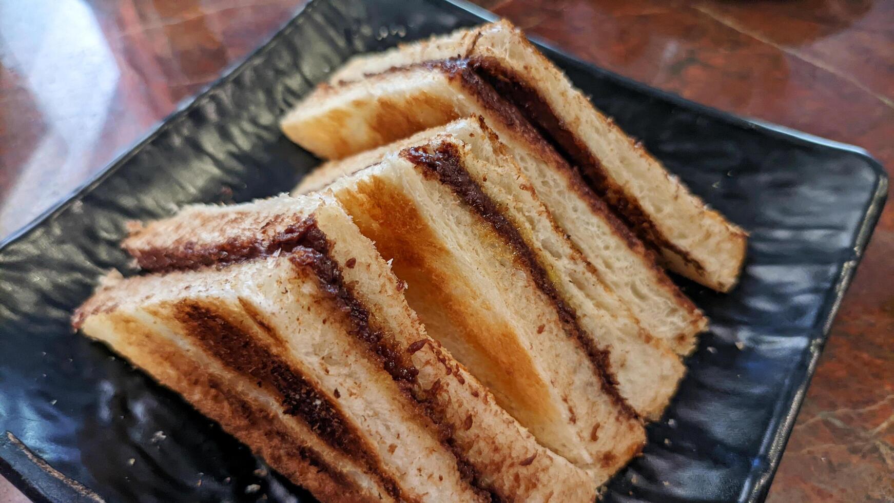 Close up of toast with homemade chocolate spread served on a black plate. photo