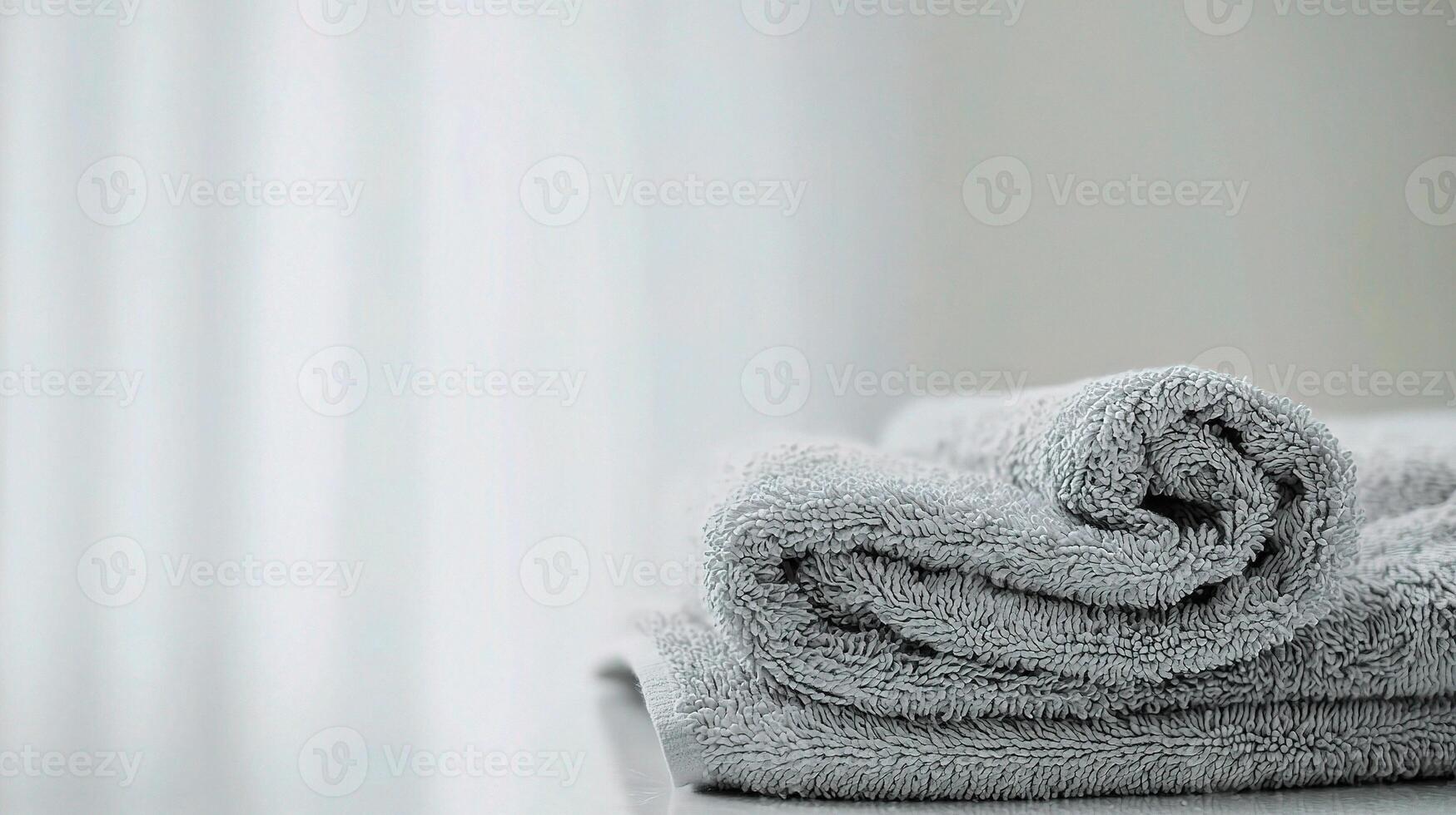 A folded towel on a table in front of a window photo