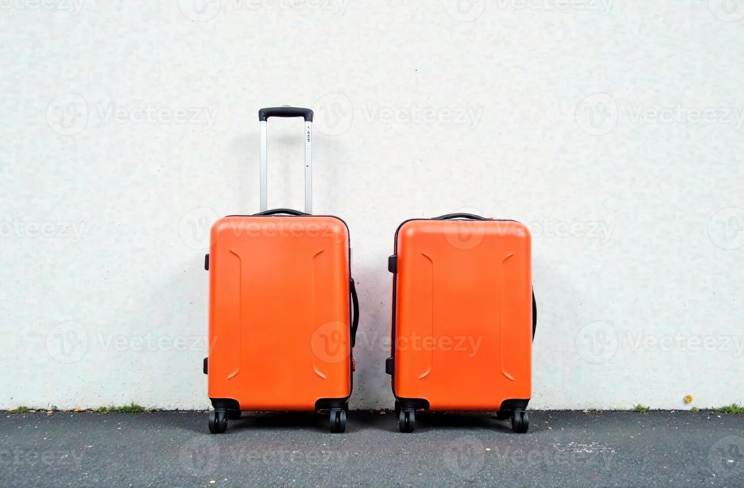 Two luggage suitcases on wheels against white wall, vacation photo