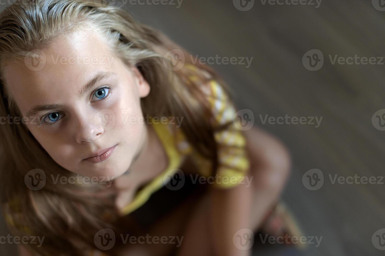 A teenage girlsits on the floor and looks up, closeup portrait photo