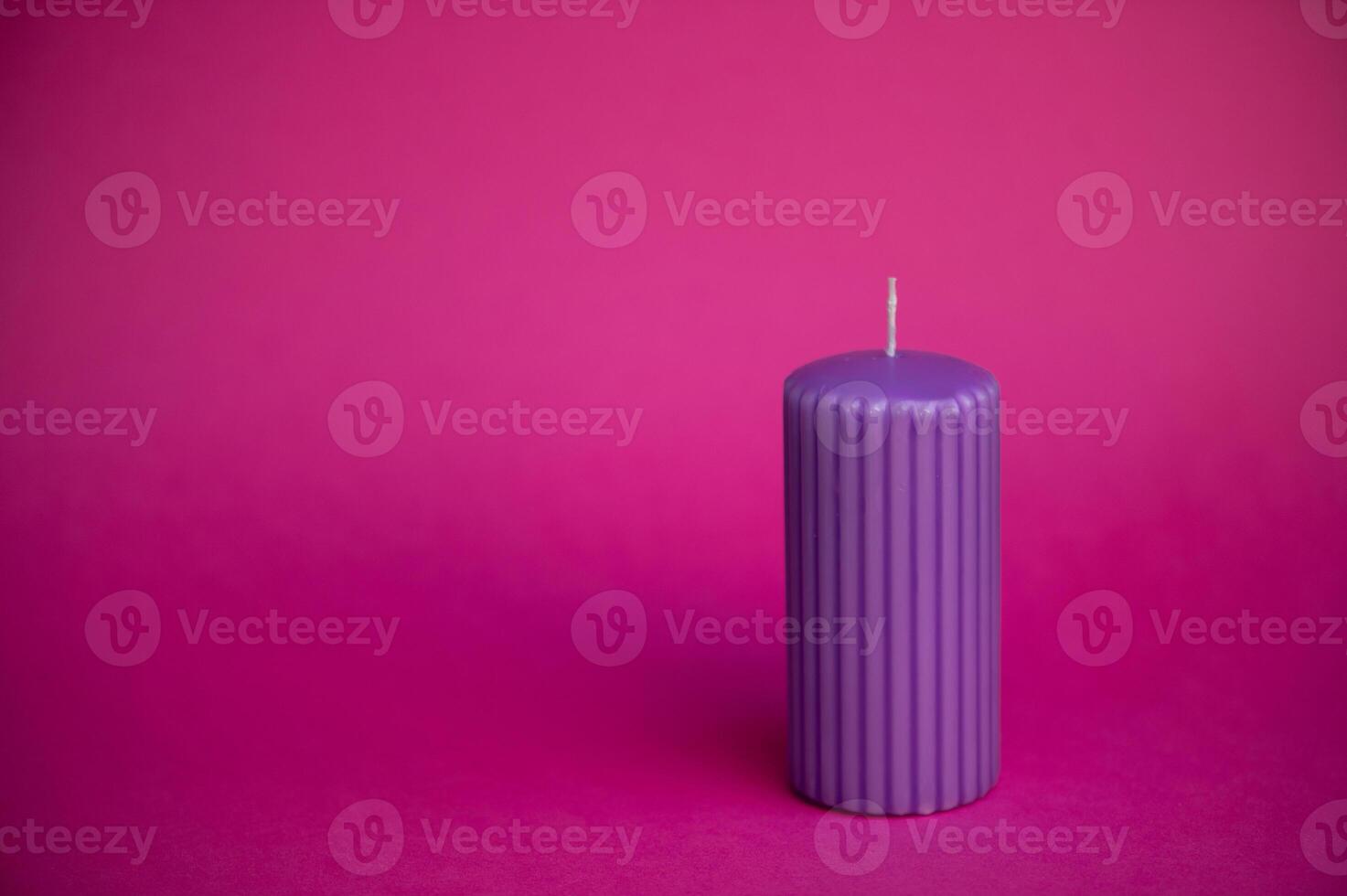 Burning blue candle with orange flame over purple background photo