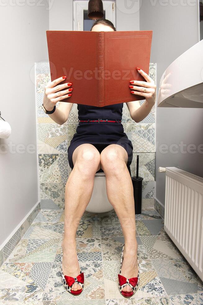 Sexy woman reading and praying over Bible in toilet photo