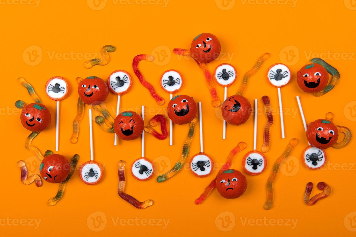 Halloween candy with black spiders and cobweb on orange color background photo