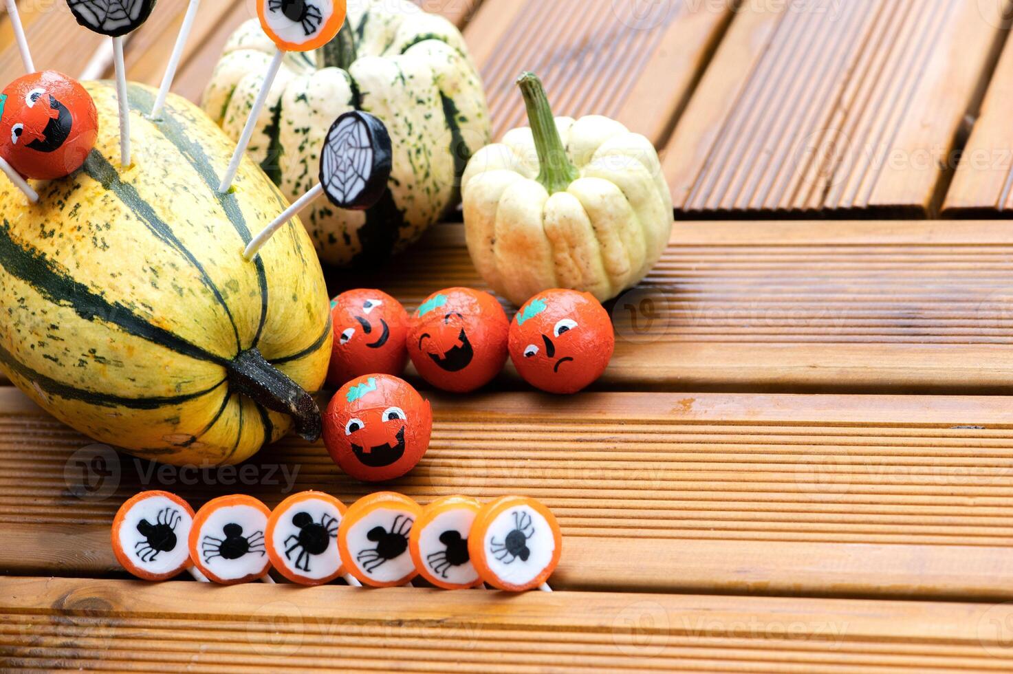 Halloween decorations background with pumpkins and sweets candies on wooden terrace photo