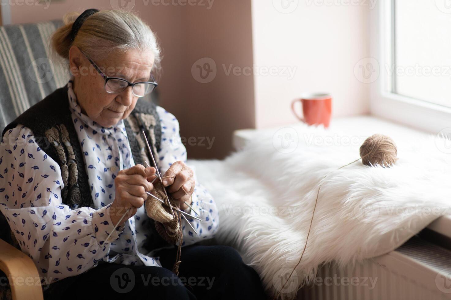 old woman knitting in nursing home by the window photo