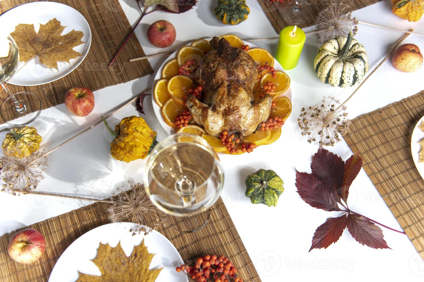 Thanksgiving roast turkey decorated with orange slices and rowan berries, top view on festive dinner table with leaves and candles photo