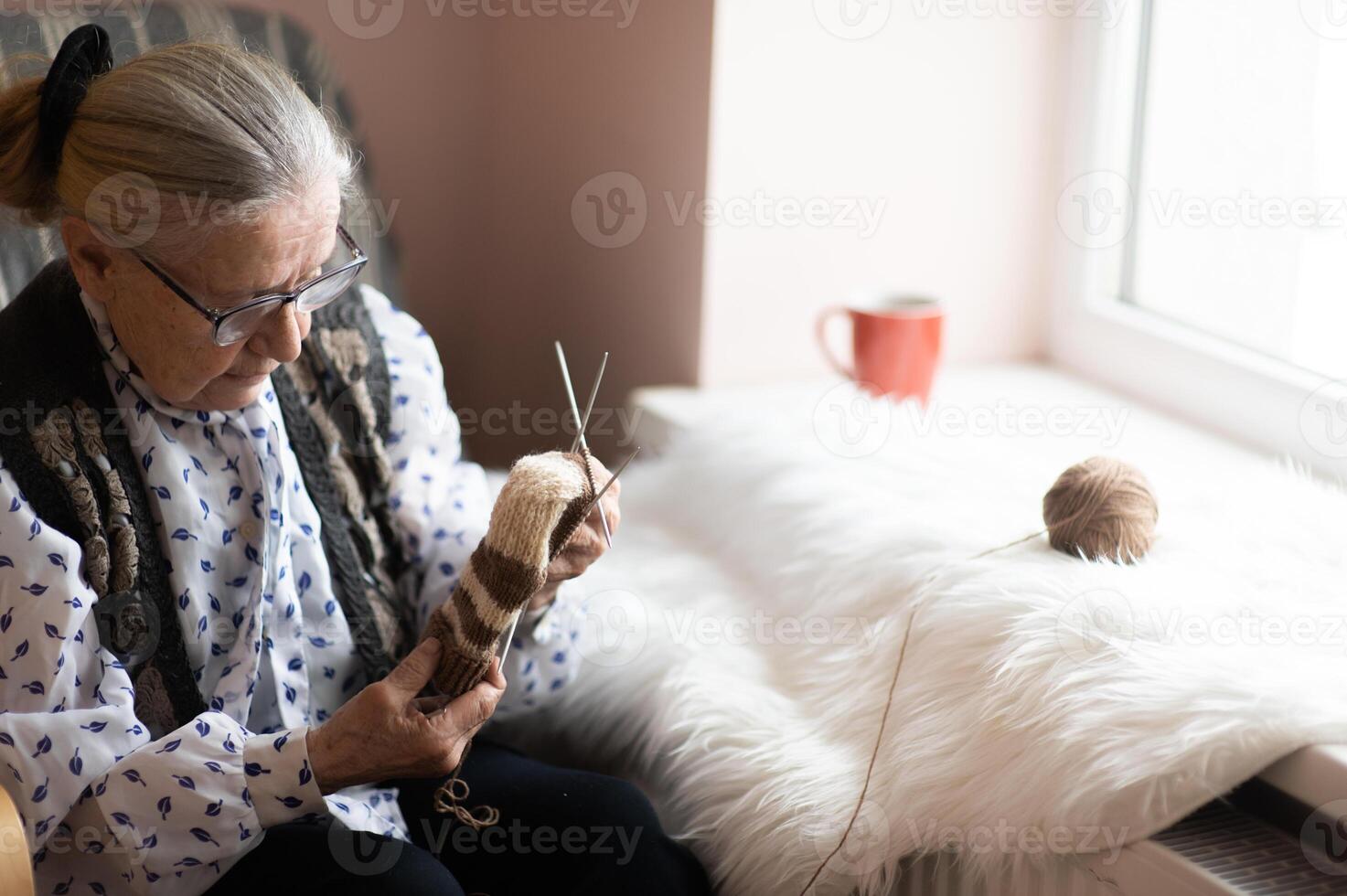 Elderly female knitting in a nursing home by the window photo