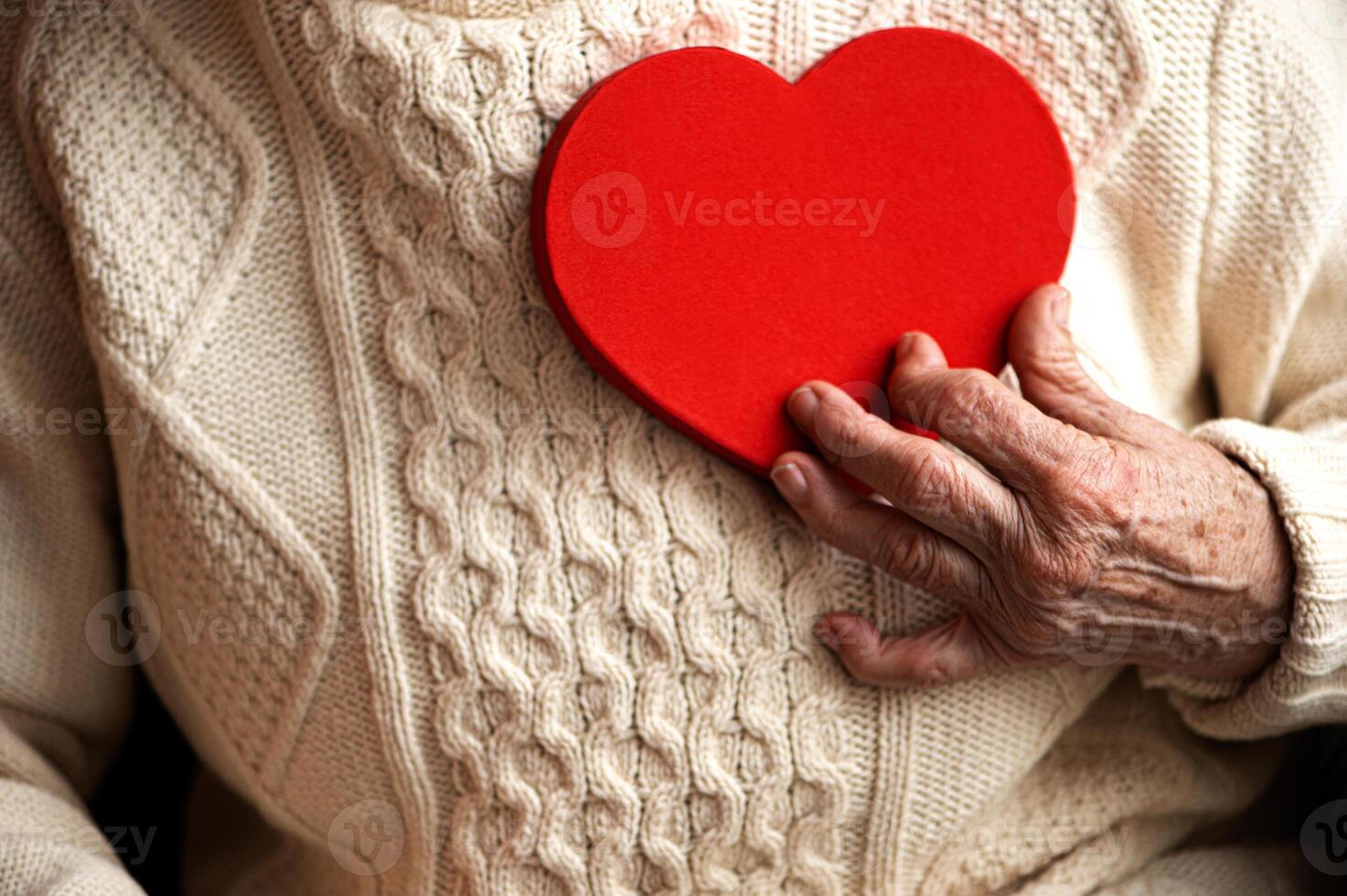 Closeup of old woman hand hold red heart - concept of heart health for elderly photo