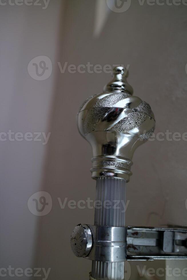 The curtain pole end cap with a round tapered shape with a chrome color, made of plastic photo