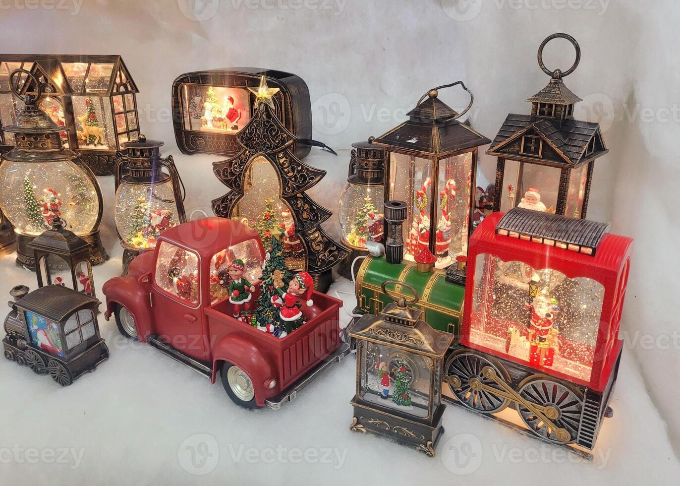Shaped Christmas glass snow lanterns on the shelf. New Years glass ball with glitter inside, lanterns, cars, Christmas trees, towers, balls standing on the rack photograph. photo