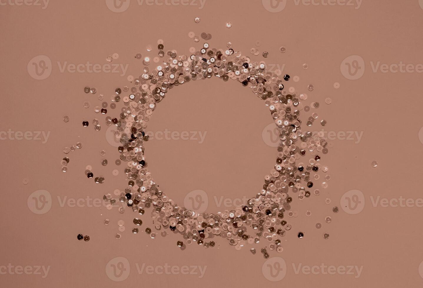 Circular arrangement of shimmery sequins on a soft pink background photo