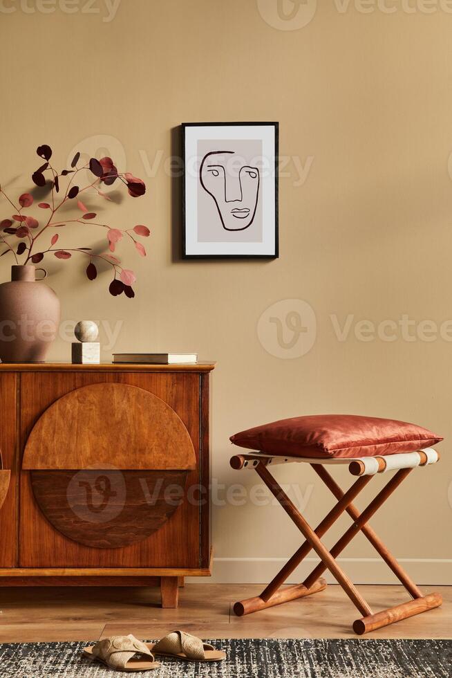 Stylish interior with design wooden commode, stool, dried flowers in vase, unique decoration, carpet, mock up poster frame and elegant personal accessories. Modern living room in classic house. photo