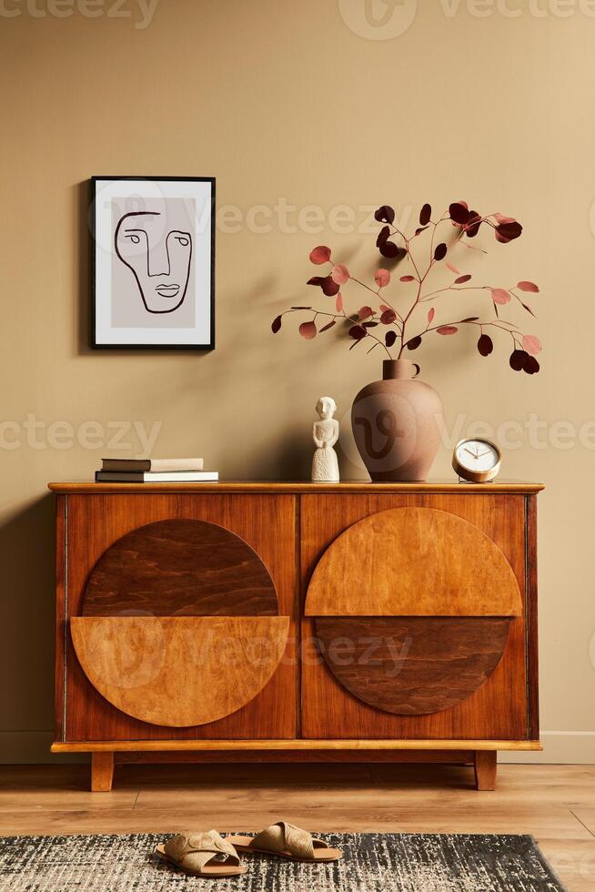 Interior design of neutral living room with stylish commode, dried flower in vase, mock up poster on the wall, carpet, decoration, clock and personal accessories in modern home decor. Template. photo