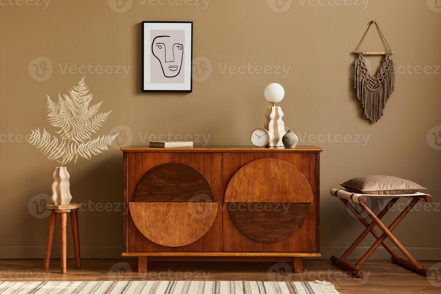 Stylish interior with design wooden commode, stool, dried flowers in vase, unique decoration, carpet, mock up poster frame and elegant personal accessories. Modern living room in classic house. photo